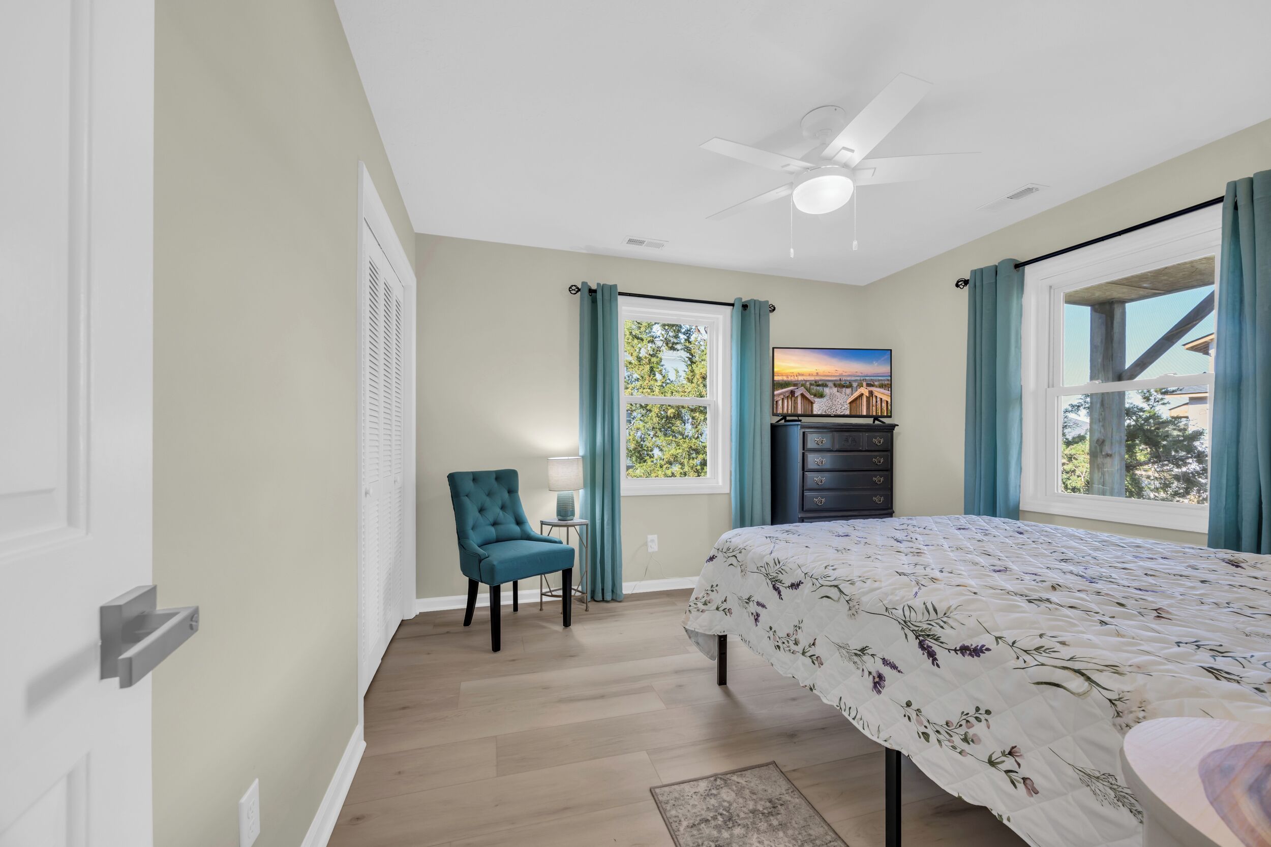 A bedroom with a bed, a chair, a dresser, and a window with curtains.
