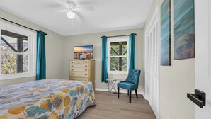 A bedroom with a bed, a dresser, a chair, a ceiling fan, and a window with curtains. - Haney's By The C - Unit C of Triplex (Pawleys Island)