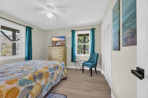 A bedroom with a bed, a dresser, a chair, a ceiling fan, and a window with curtains. - Haney's By The C - Unit C of Triplex (Pawleys Island)