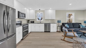 A modern kitchen with white cabinets, stainless steel appliances, and a central island. - Haney's By The C - Unit C of Triplex (Pawleys Island)