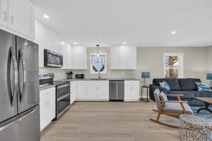A modern kitchen with white cabinets, stainless steel appliances, and a central island. - Haney's By The C - Unit C of Triplex (Pawleys Island)