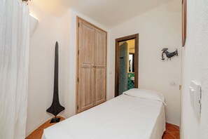 A bedroom with a bed, a wooden wardrobe, and a bathroom visible through an open door. - Villa Abbaiola - Marina Porto Cervo (Porto Cervo)