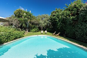 A swimming pool with clear water, surrounded by lush greenery and trees. - Villa Abbaiola - Porto Cervo Marina (Porto Cervo)