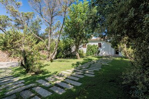 Ein Garten mit einem gepflasterten Weg, der zu einem weißen Gebäude mit einem Ziegeldach führt.
