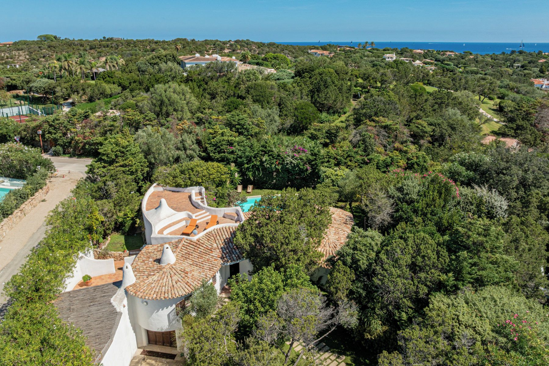 Eine Villa mit Schwimmbad, umgeben von üppiger Vegetation mit Blick auf die Küste.