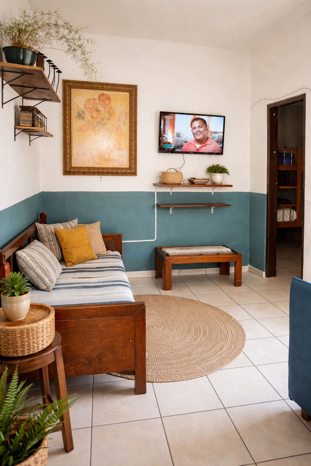 A cozy living room with a sofa, a television, shelves with decorative items, and a large painting on the wall.