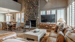 Amplia sala de estar con chimenea de piedra, un televisor de pantalla plana grande y una zona de estar cómoda con un sofá y sillones.