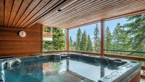 Jacuzzi con terraza de madera y vista a árboles.