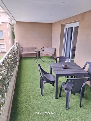 A balcony with artificial grass, a table, chairs, and a sofa.