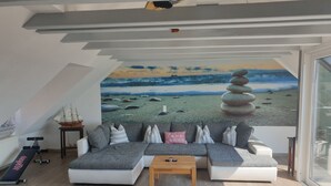 Una sala de estar moderna con un sofá seccional, una mesa de centro y un mural con una escena de playa.