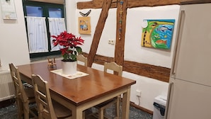 Una mesa de madera con sillas, una planta en maceta y un cuadro en la pared.