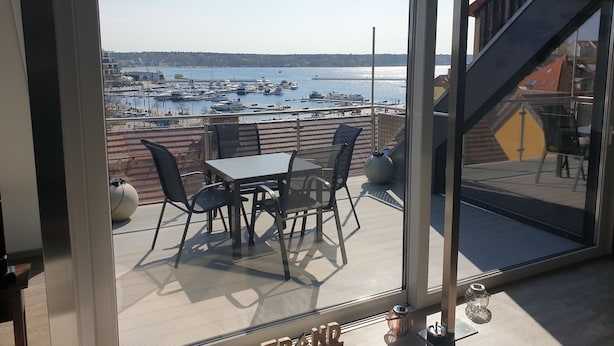 Un balcón con mesa y sillas con vistas a un puerto deportivo con barcos.