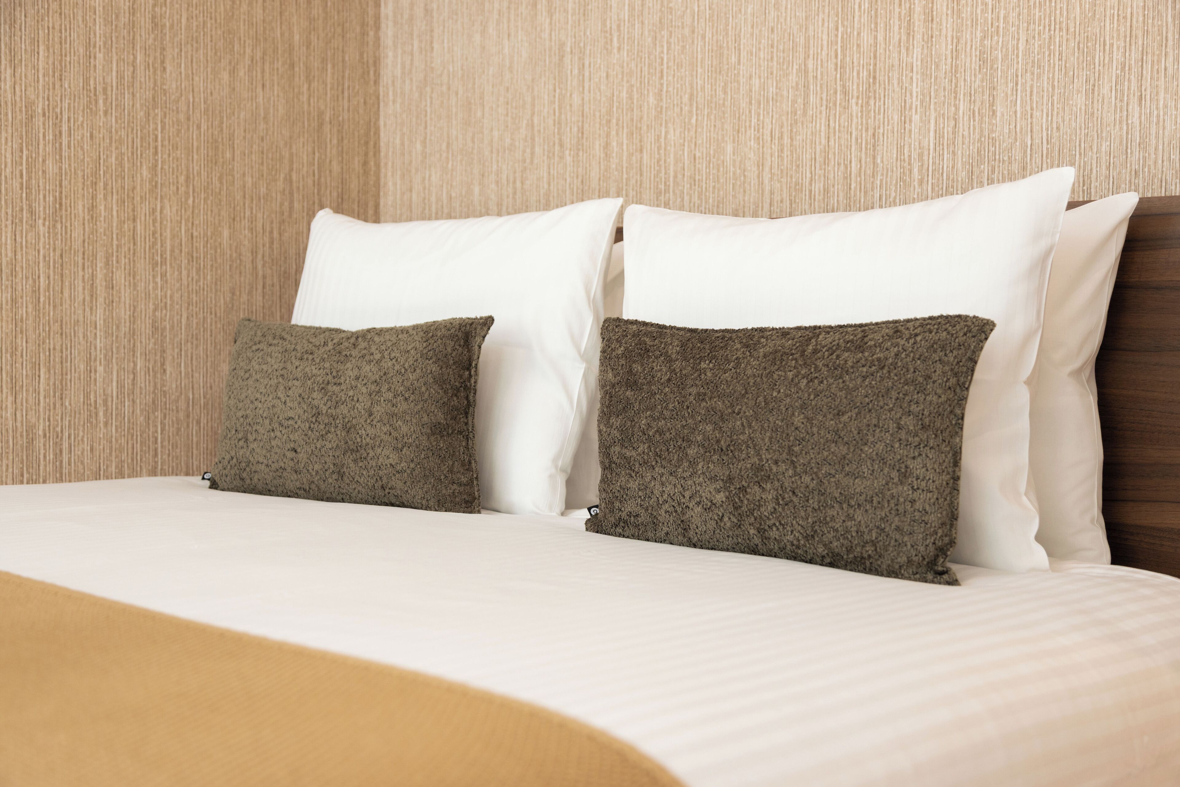 Ein Hotelzimmer mit einem Bett, zwei Kissen und einem hölzernen Kopfteil.