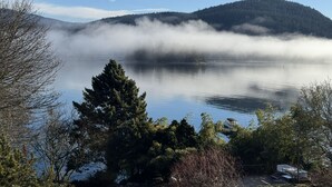 En rolig sø med en skovklædt bakke i baggrunden og en klar himmel.