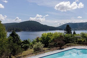 A swimming pool with a view of a lake and mountains.