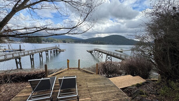 Une jetée en bois s’étendant sur un lac paisible, avec des montagnes en arrière-plan.