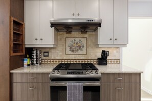 A kitchen with a stainless steel range, a backsplash with a mosaic design, and wooden cabinets.