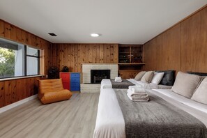 A modern living room with a fireplace, wooden walls, a sofa, a red cabinet, and a window.