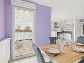 A dining area with a table set for four, a kitchen in the background, and a sliding glass door leading to an outdoor balcony. - Apartment for 4 in the heart of La Baule (La Baule-Escoublac)