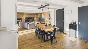 A modern kitchen with a stone wall, wooden flooring, and a dining area with a wooden table and chairs.