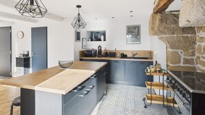 A modern kitchen with a central island, a stone accent wall, and a hanging light fixture.