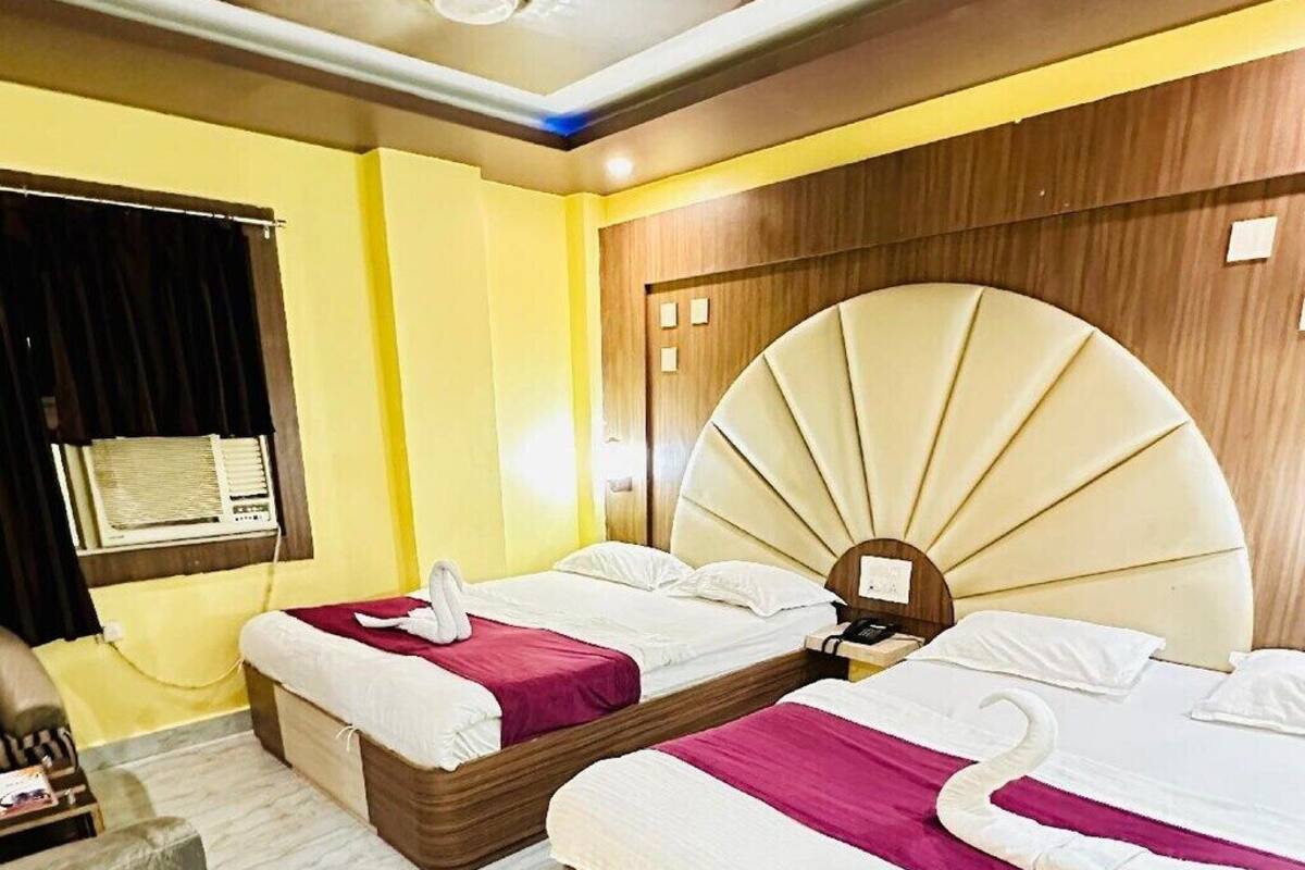 A hotel room with two beds, a wooden headboard, a green rug, and a ceiling fan.