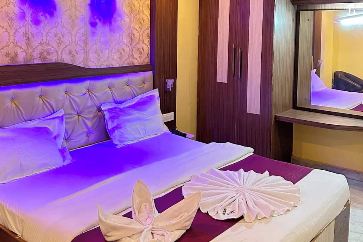 A hotel room with a large bed, a ceiling fan, and a mirror.