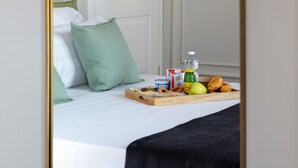 Een hotelkamer met een bed, een dienblad met ontbijtartikelen, een fles en een kop.