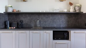 Een moderne keuken met een zwart aanrecht, witte kastjes, een magnetron en een spoelbak.