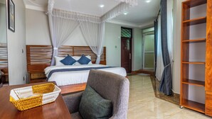 A hotel room with a bed, a chair, a wooden side table, a wicker basket, and a wardrobe. - VALLEY BLOOM HOTEL KYANJA (Kampala)