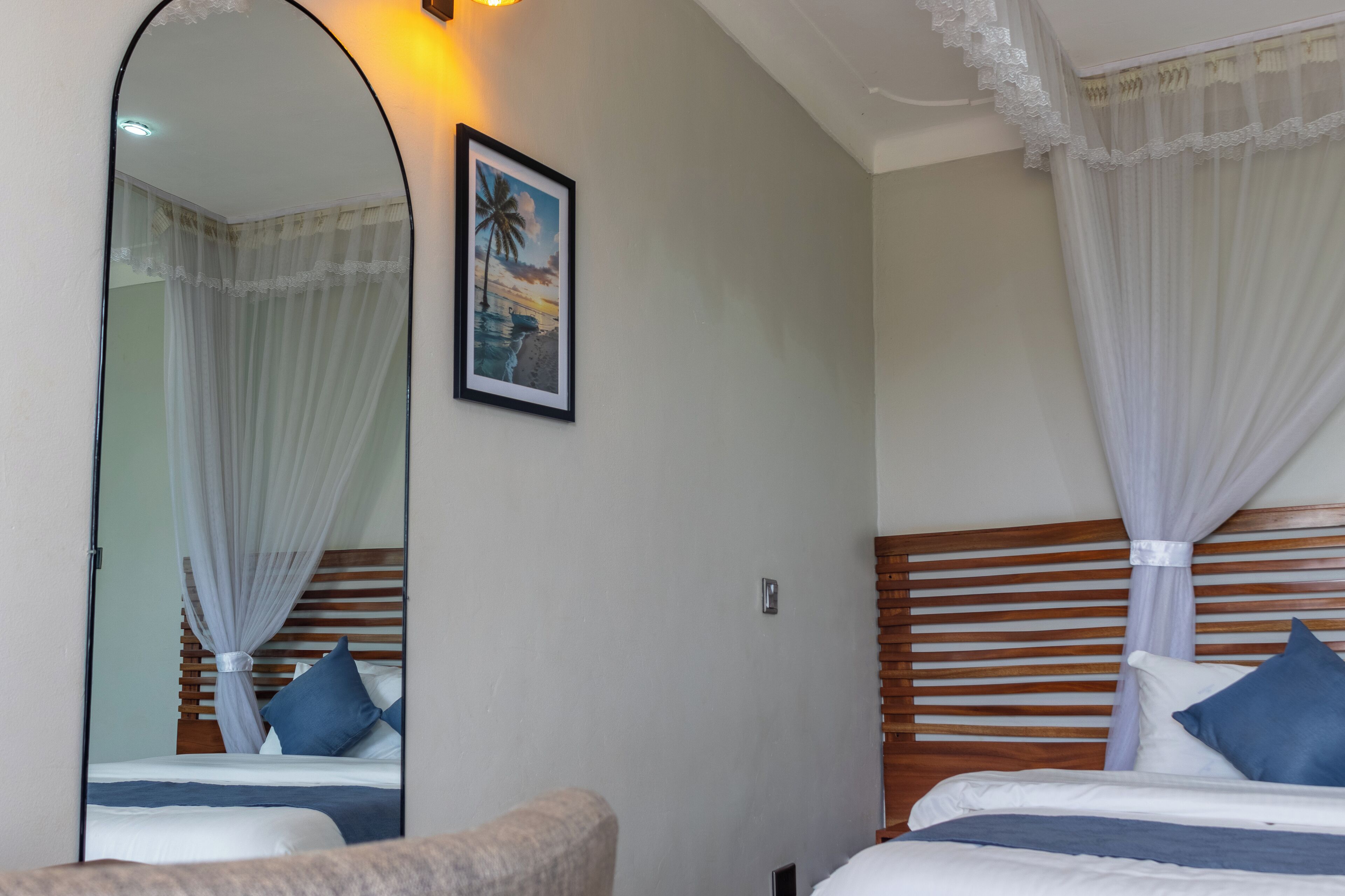 Una camera d'albergo con due letti, un grande specchio e un quadro appeso al muro.
