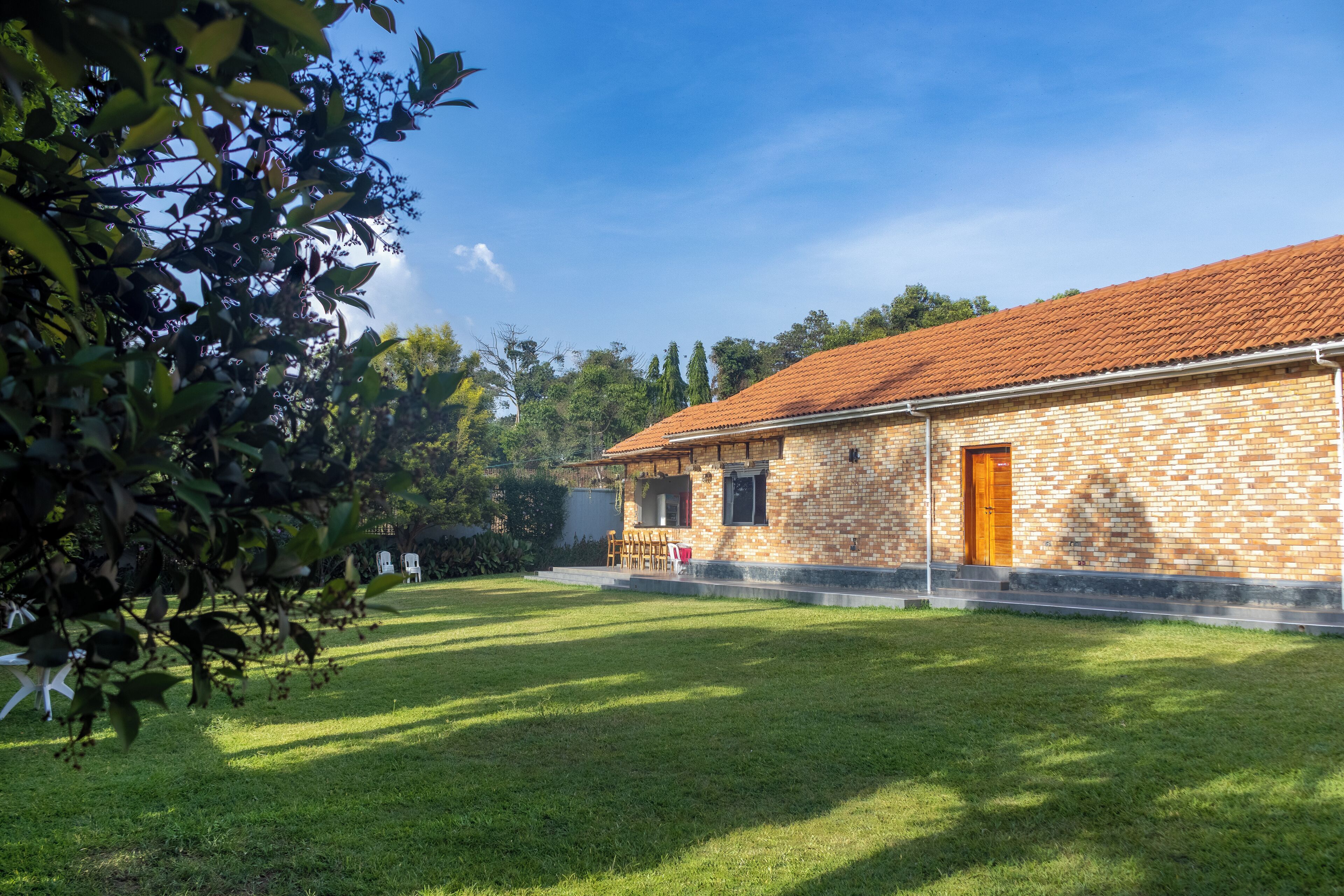 A brick building with a tiled roof, a covered porch, and a well-maintained lawn.