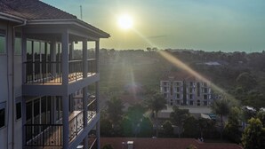 A multi-story building with balconies, a clear view of the surrounding neighborhood, and the sun shining through the windows. - VALLEY BLOOM HOTEL KYANJA (Kampala)