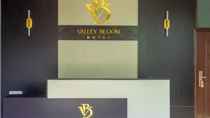 A reception desk with the Valley Bloom Hotel logo and name. - VALLEY BLOOM HOTEL KYANJA (Kampala)