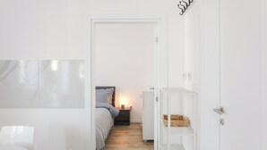 A modern, minimalist bedroom with a bed, bedside table, and a nightstand with a lamp.