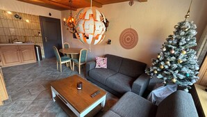Ein gemütliches Wohnzimmer mit einem grauen Sofa, einem Holztisch und einem Weihnachtsbaum.
