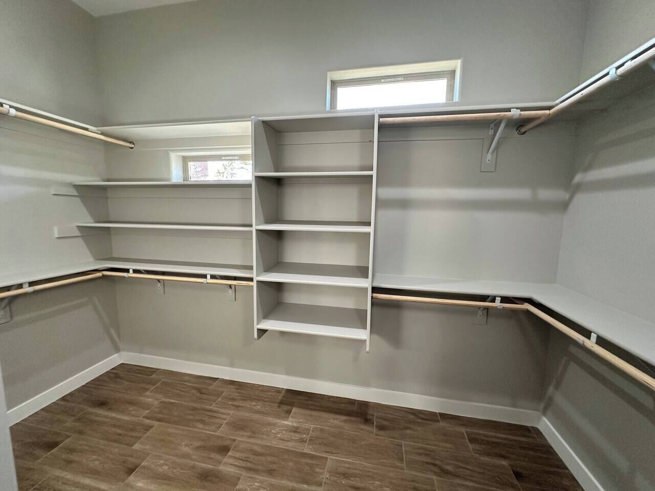 Ein begehbarer Kleiderschrank mit eingebauten Regalen und einer Leiter, grauen Wänden und Holzböden.