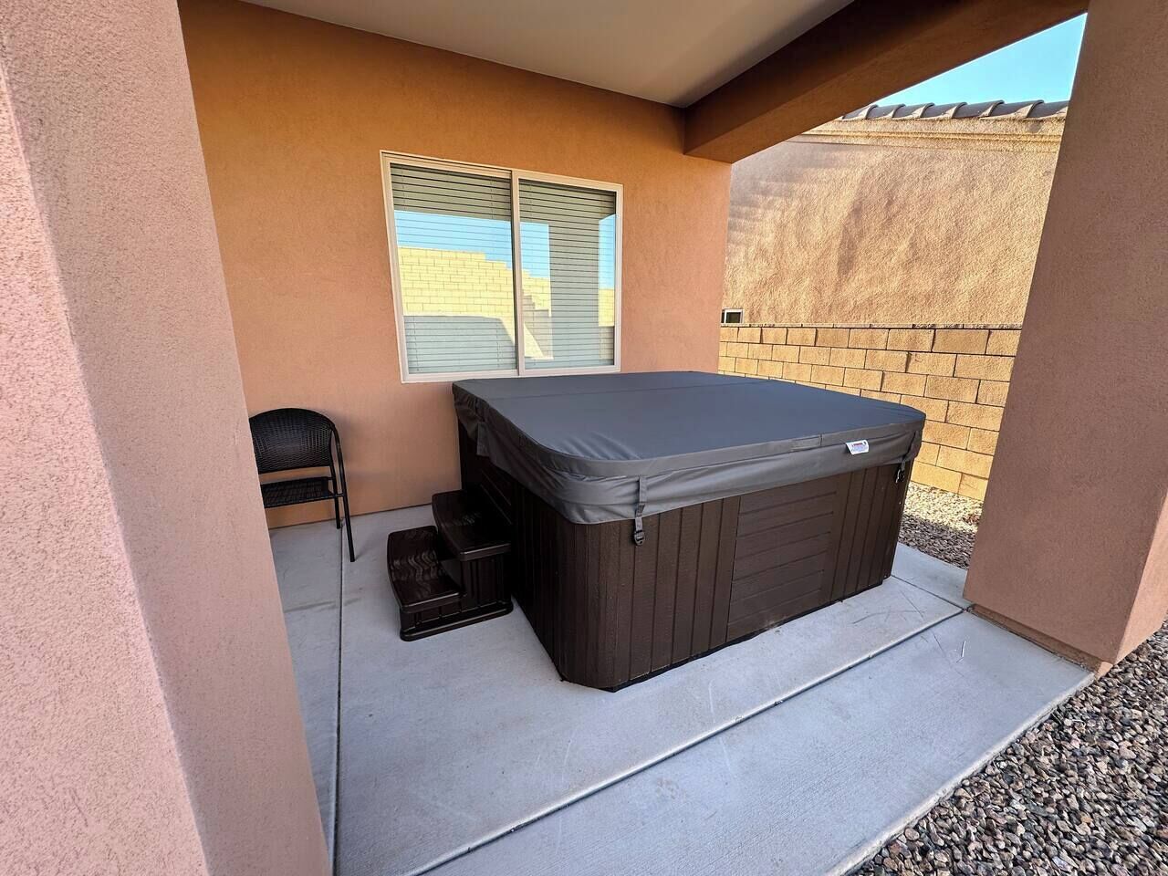 Ein Whirlpool auf einer Terrasse mit einem Stuhl und einem kleinen Tisch.