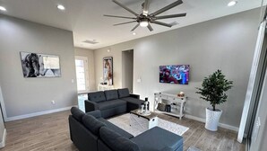 A modern living room with a sectional sofa, a coffee table, a TV, and a ceiling fan.