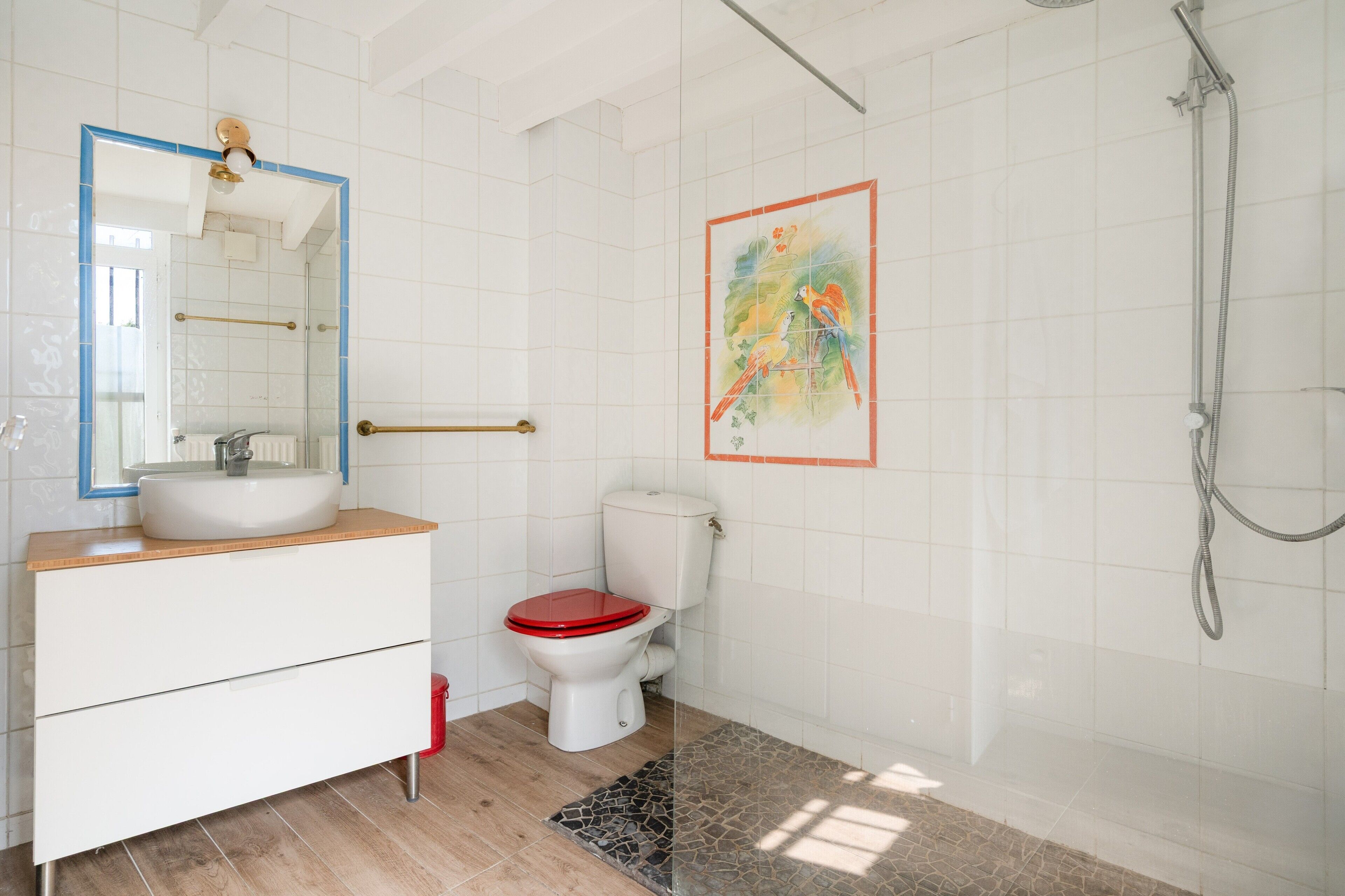 Une salle de bain avec un lavabo blanc, des toilettes rouges et une douche.
