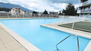 Una piscina con una scala in metallo e ringhiere bianche, circondata da un recinto bianco.