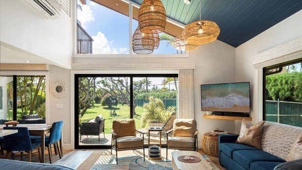 Un salón amplio con un televisor grande, asientos cómodos y vistas a un jardín exuberante.