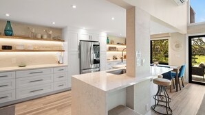 Una cocina moderna con armarios blancos, encimera de mármol y una isla integrada con taburetes de bar.