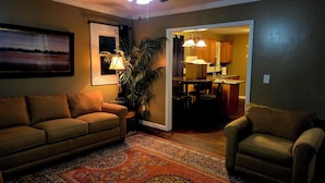 A living room with a sofa, armchair, and a patterned rug.