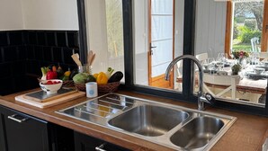 Een moderne keuken met een grote spiegel, een roestvrijstalen spoelbak en zwarte keukenkastjes.