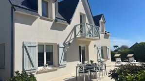 Een groot huis met een balkon, een eethoek met tuinmeubilair en een tuin.