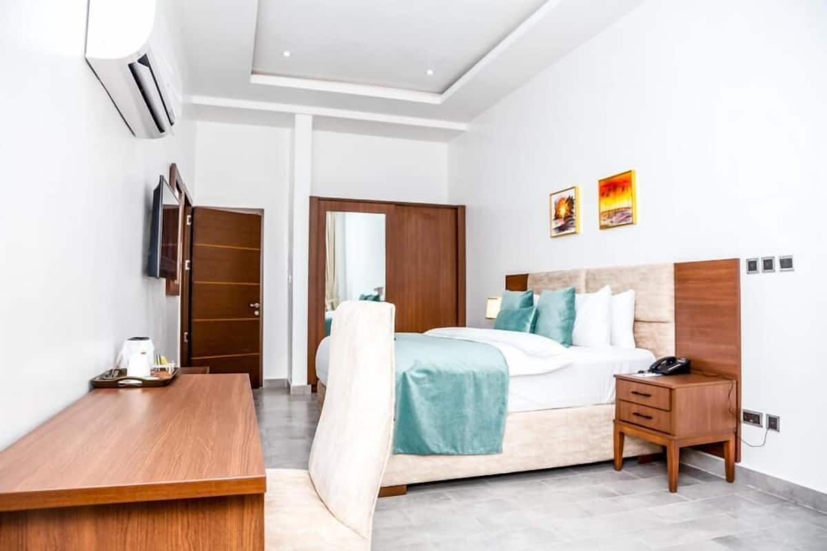 Une chambre d’hôtel comprenant un lit, une table de chevet, une commode et un bureau avec une chaise.