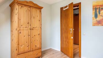 A room with a wooden wardrobe and a door leading to another room.