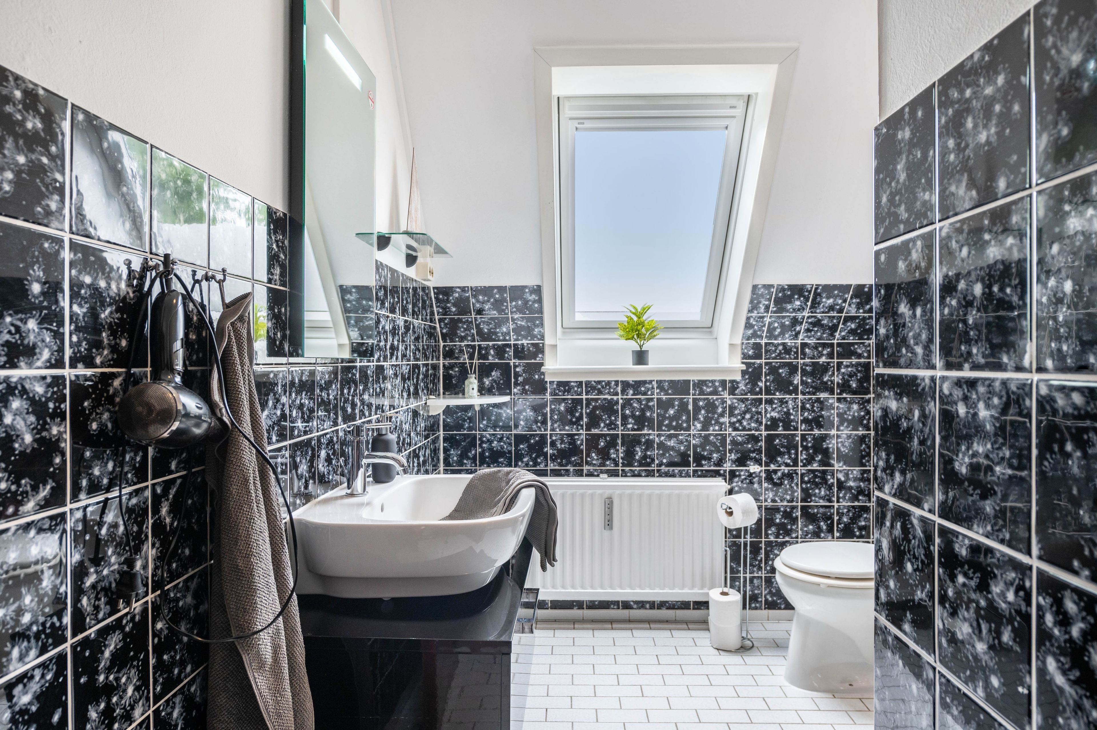 A modern bathroom with a freestanding bathtub, a toilet, and a window providing natural light.