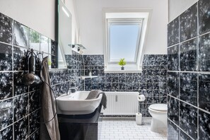 Ein modernes Badezimmer mit Oberlicht, einer Badewanne, einer Toilette und einem Waschbecken.